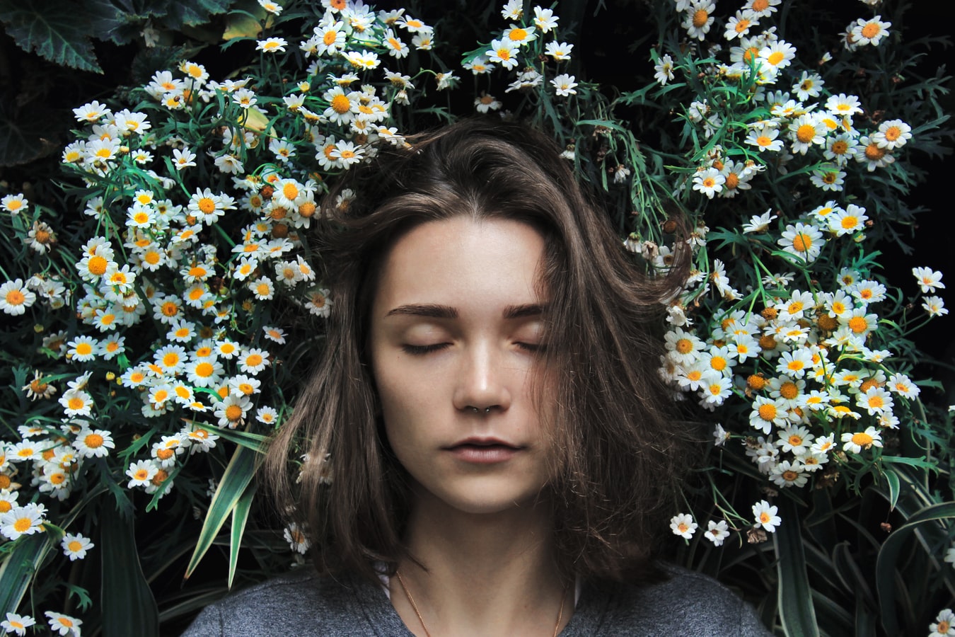 girl with closed ones surrounded by small white flowers